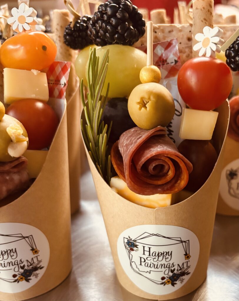 A display of mini charcuterie cups featuring meats, cheeses and various appetizers for a light snack.