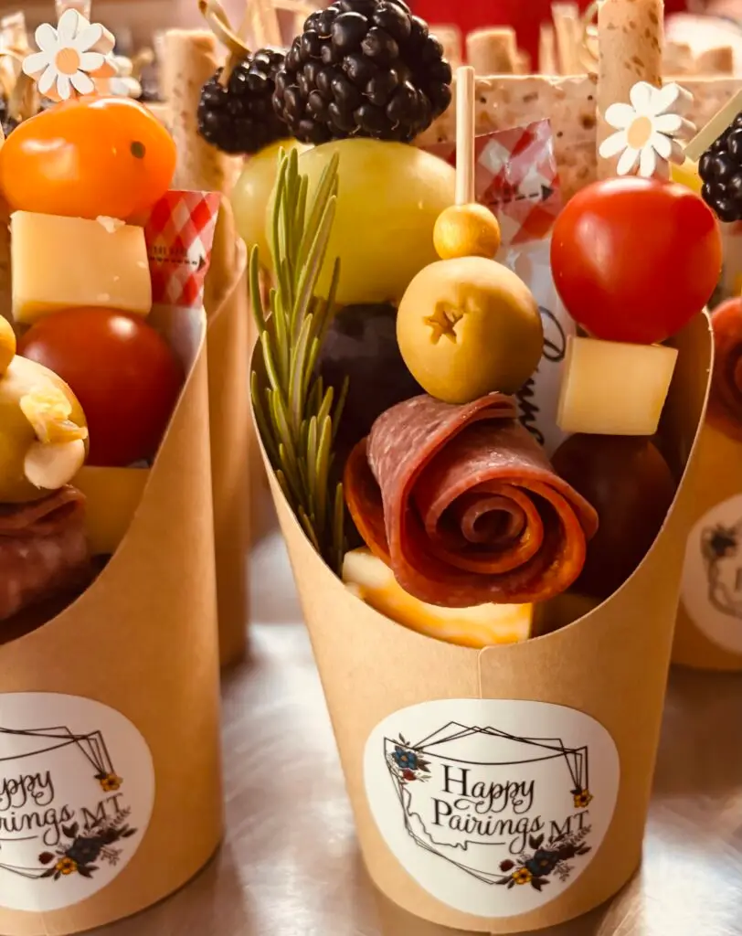 A display of mini charcuterie cups featuring meats, cheeses and various appetizers for a light snack.