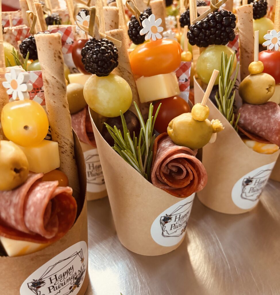 A display of mini charcuterie cups featuring meats, cheeses and various appetizers for a light snack.
