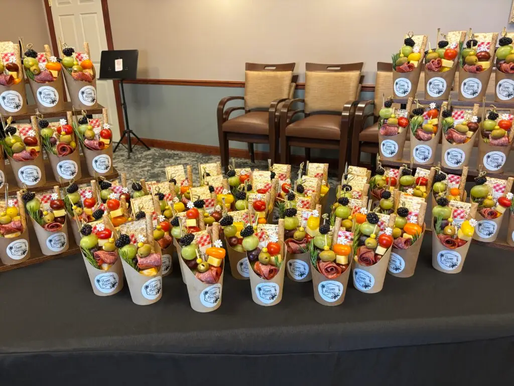 A display of mini charcuterie cups featuring meats, cheeses and various appetizers for a light snack.